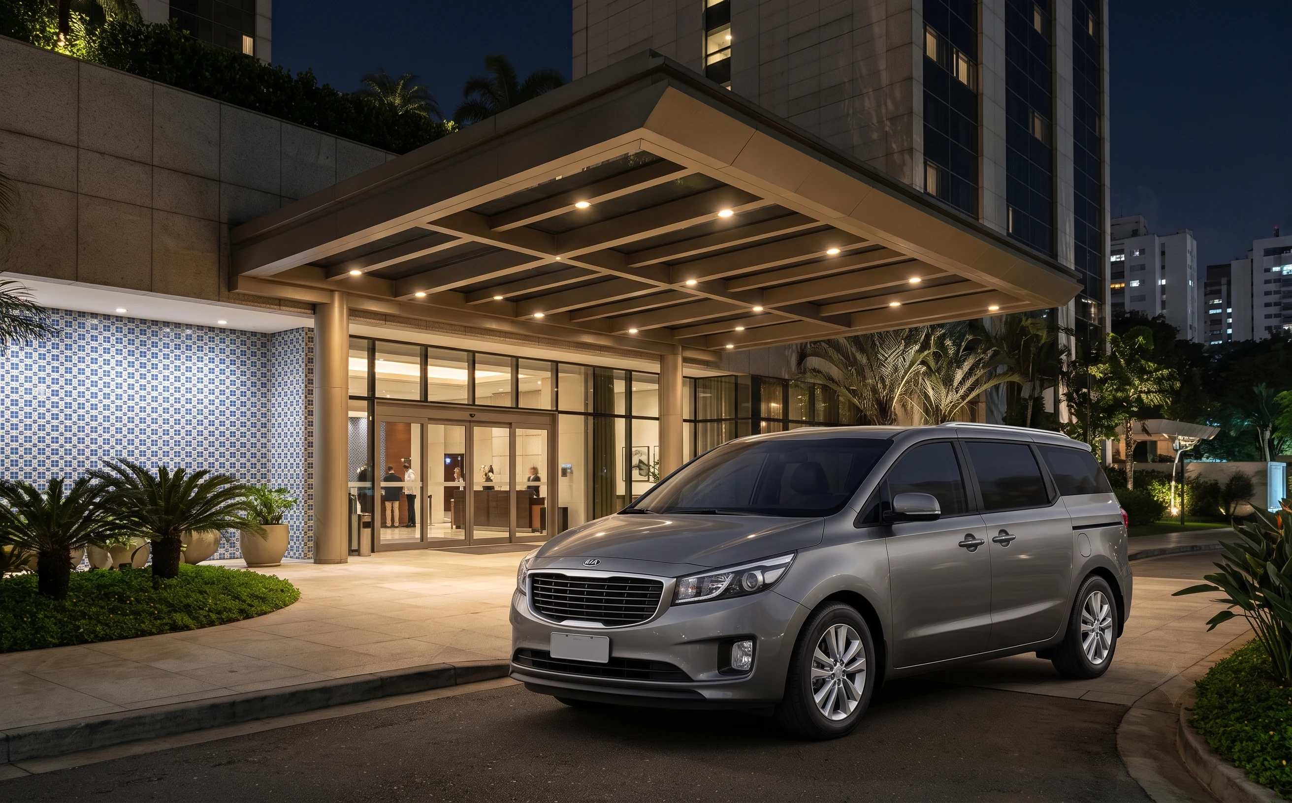Illustrative gray Kia Carnival at a composed São Paulo hotel porte-cochère at night